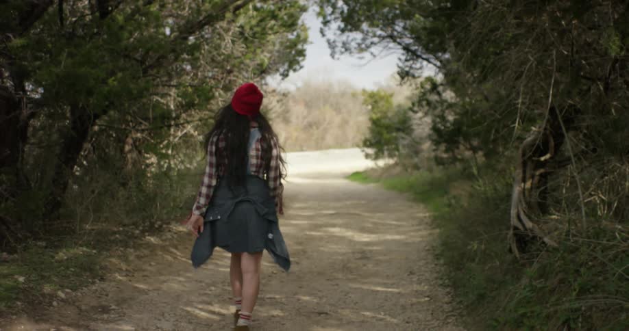 A woman walking down a tree-lined dirt road