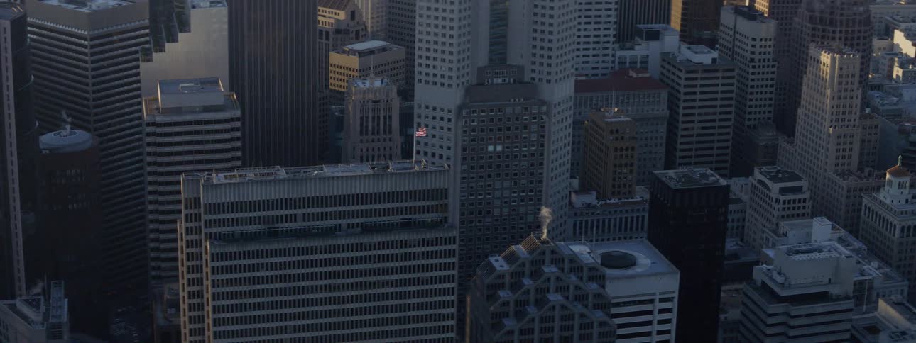 An american flag flies on the roof of a tall building in a downtown part of a city