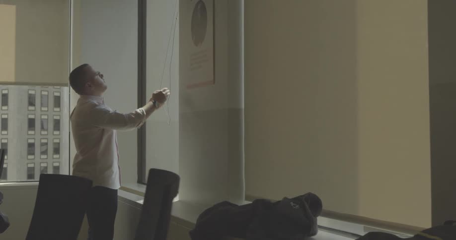 A man closes the blinds in the office