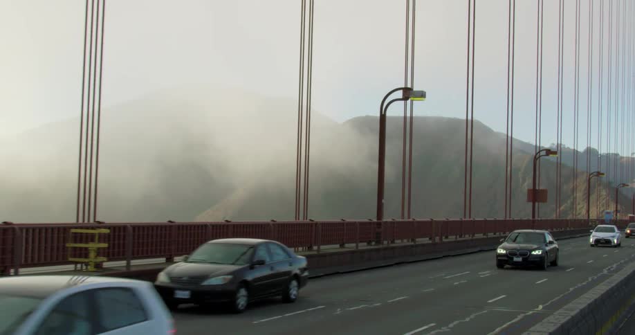 Cars cross the golden gate bridge at dawn