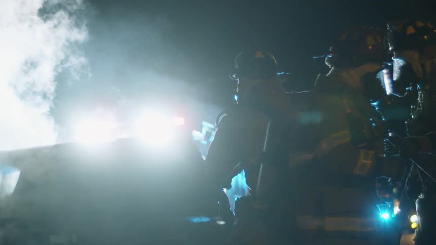 Firemen are outdoors at night responding to a scene
