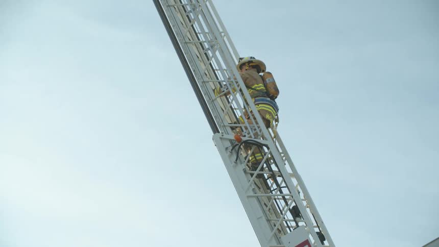 A firefighter climbs a ladder