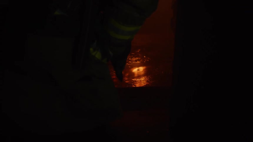 A firefighter stands by a puddle reflecting a fire