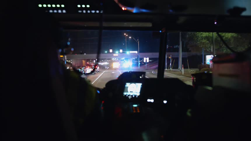 A firefighter drives a fire truck down a city street