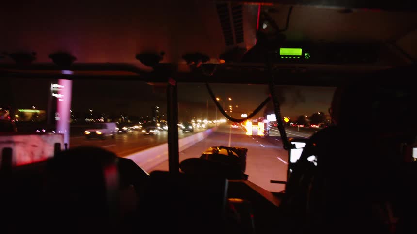 Firefighters drive their truck down a busy city highway at night