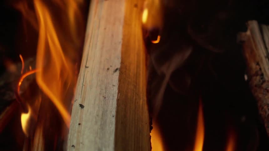 Flames flicker past a log