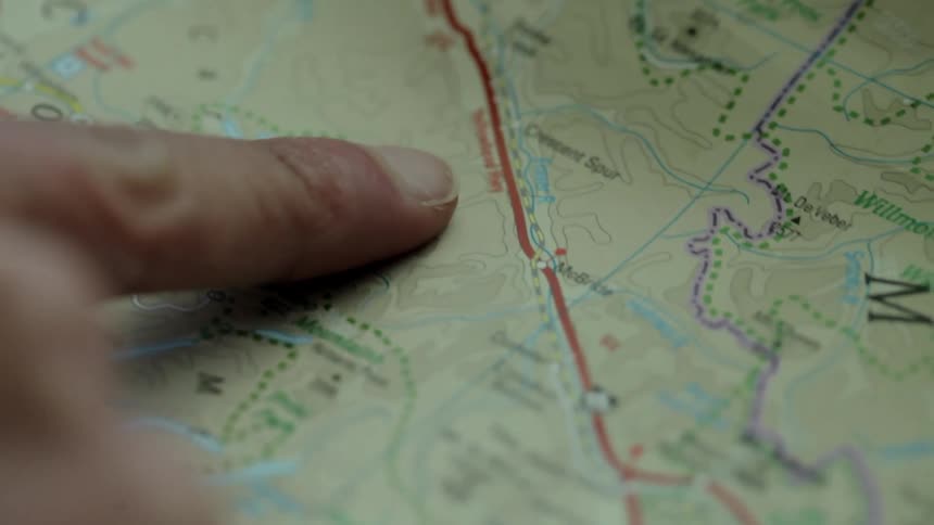 A person is putting their finger on a map and tracing it