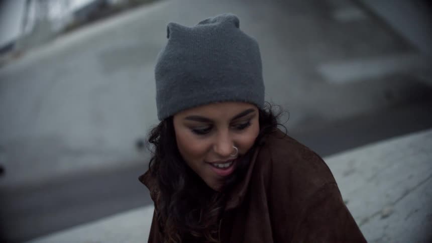 A young woman sits outside and looks around and smiles