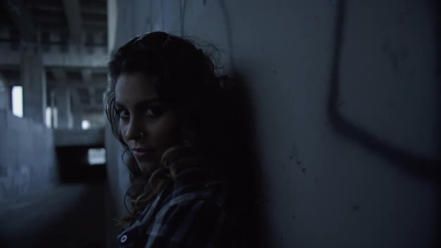 A woman leans against a wall leading in to a tunnel