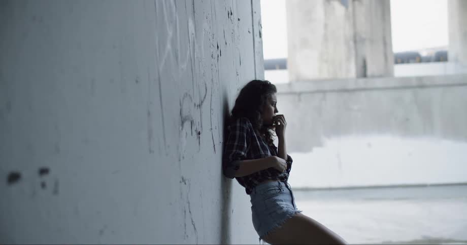 A woman is leaning against the cement wall