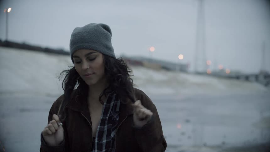 A teenager holds on to her hair and looks around her surroundings