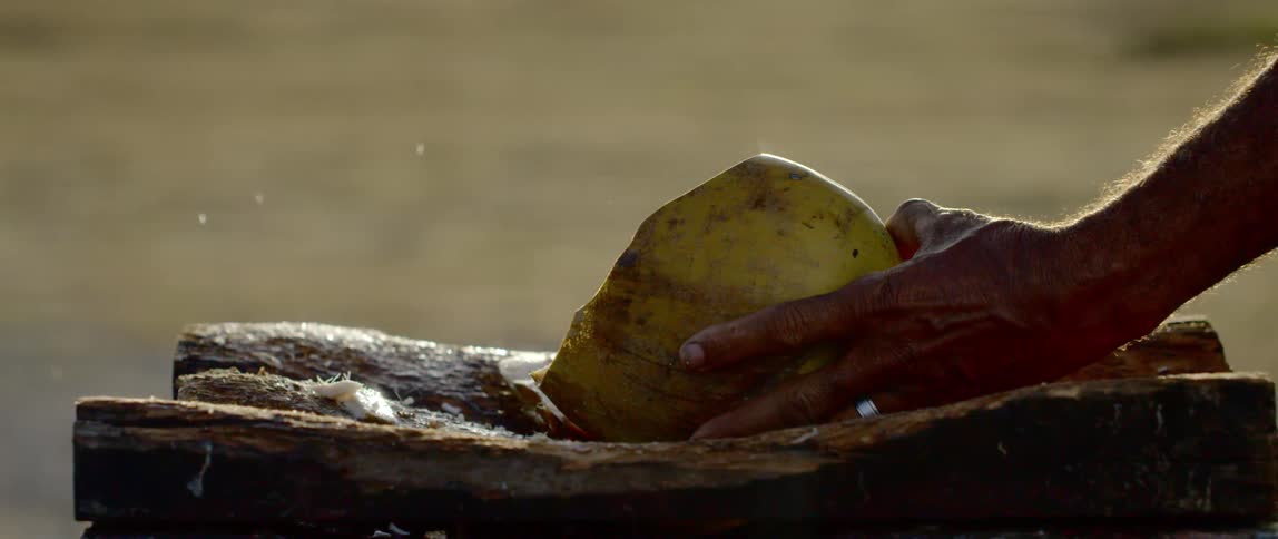 A man chops a fruit with a large knife