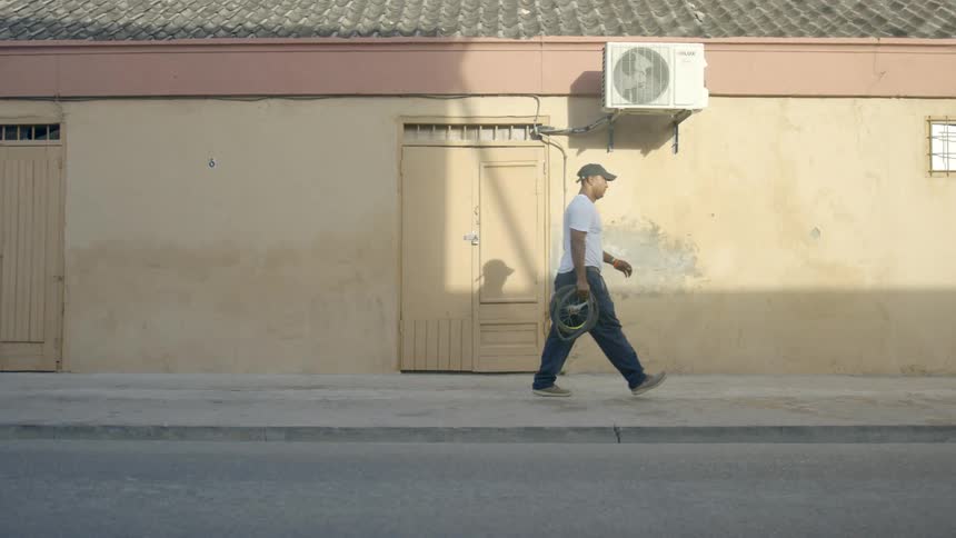A man walks down a street carrying bike tires