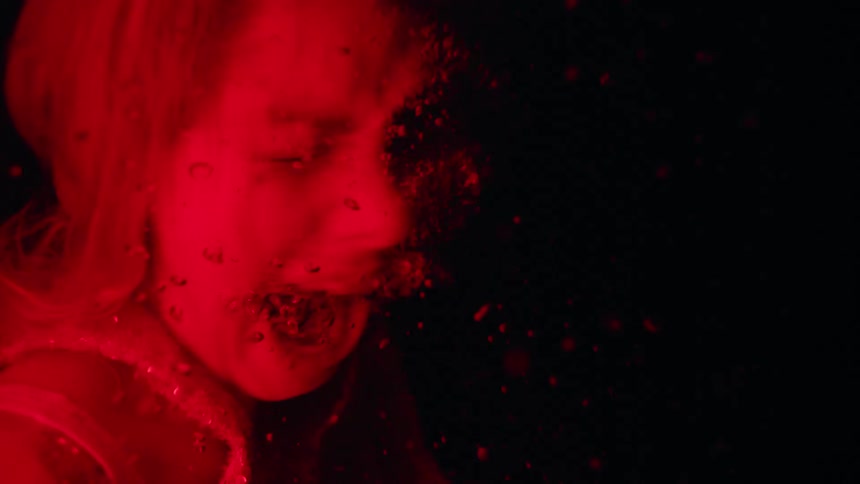 Underwater footage of woman screaming under red light and flashes
