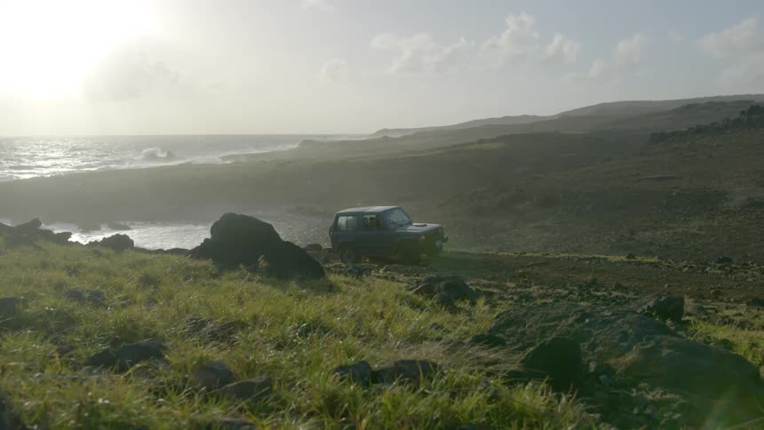 A jeep slowly traveling off road across rocky hilly terrain
