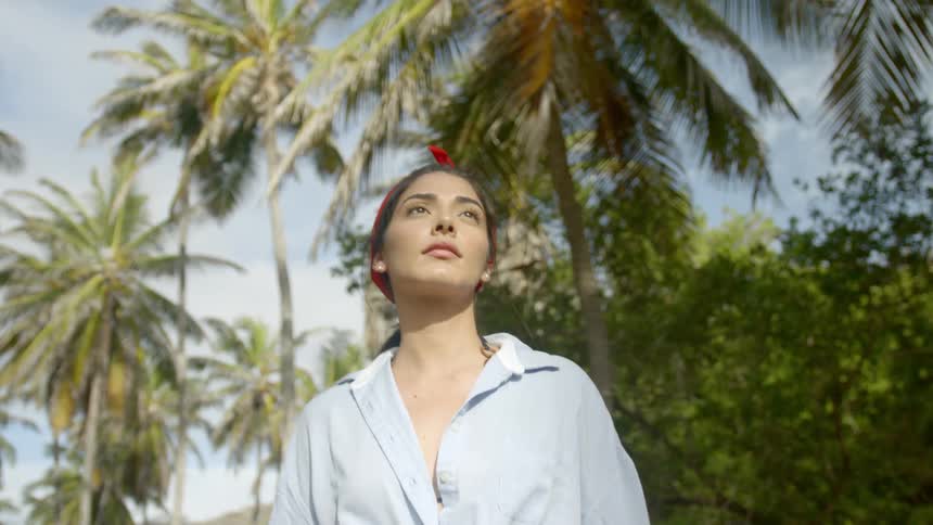 Woman wearing pony tail and bandana walks past palm trees