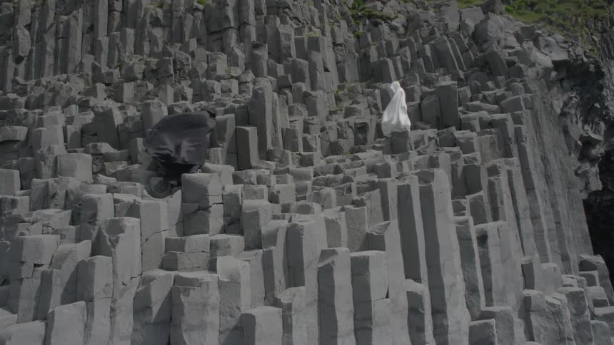 Two cloaked figures standing on rock pillars