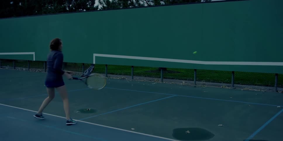 A woman practicing tennis against a wall