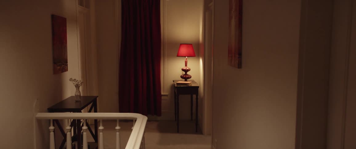 A white woman walks around the corner of a hallway in a house