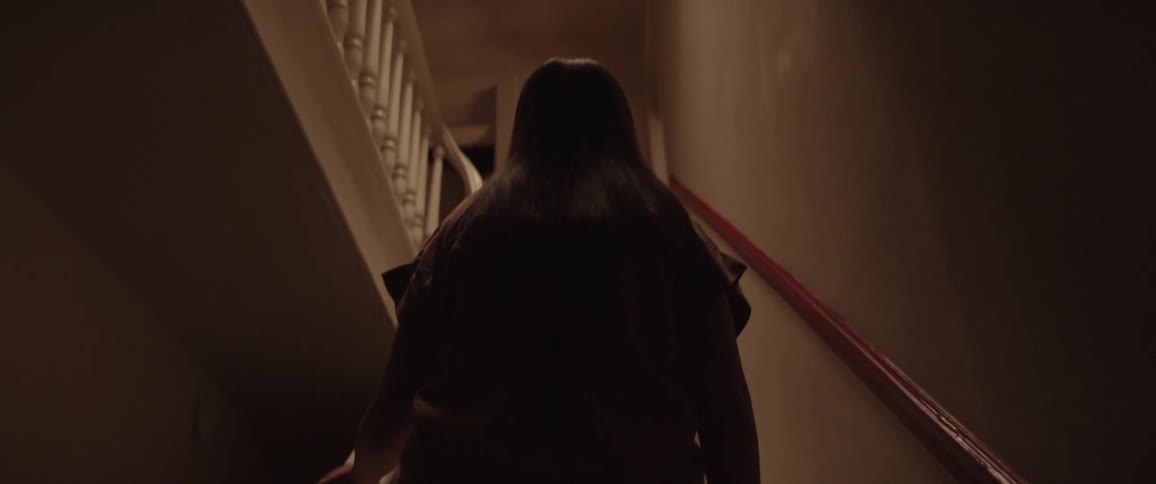 A white woman climbs a narrow staircase in a home