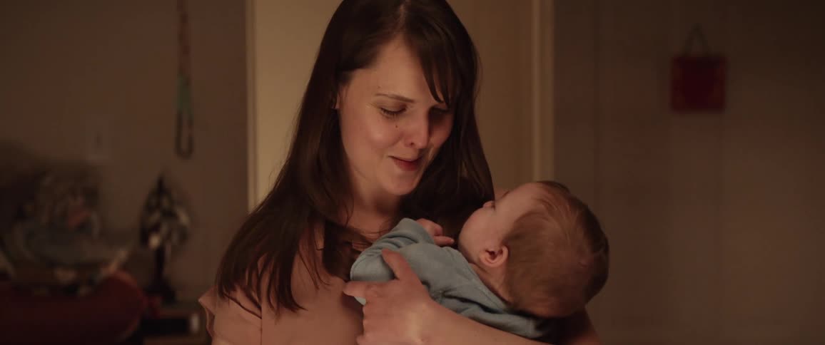 A mother is holding her baby indoors