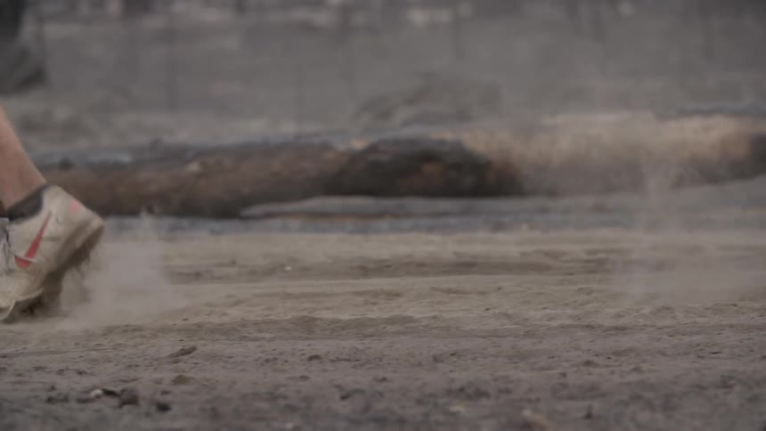A man is running over some dirt