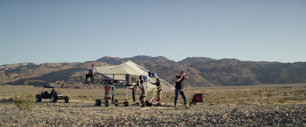 A man pulling something with a strap with people with cameras and lights in the background