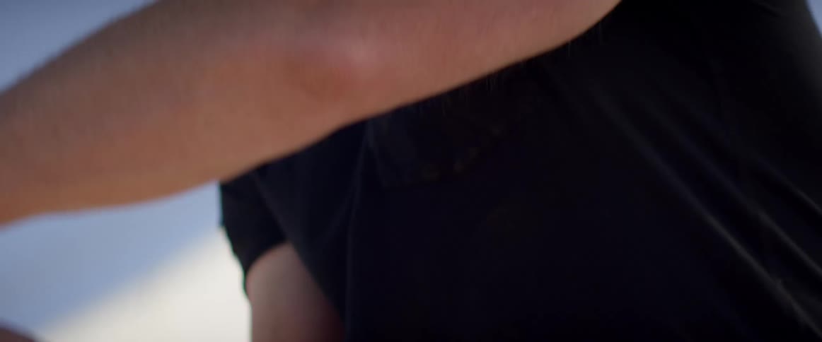 A man takes two strap handles and pulls them together over his shoulder and strains to pull and haul