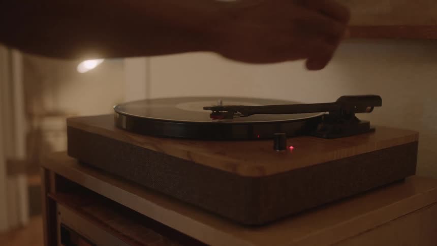 A person puts the needle on the record player