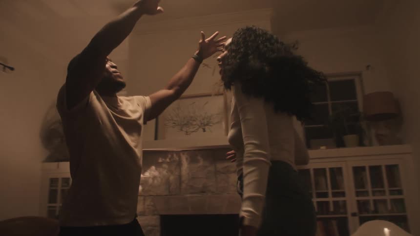 A man and woman jumping and dancing in celebration in the living room of a house