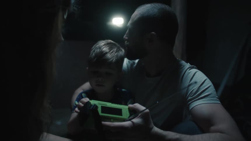 A family huddles together with a radio in a basement
