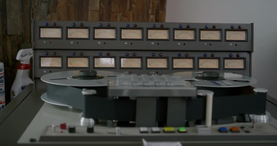 Tape reels spinning on a large machine with many buttons and meters
