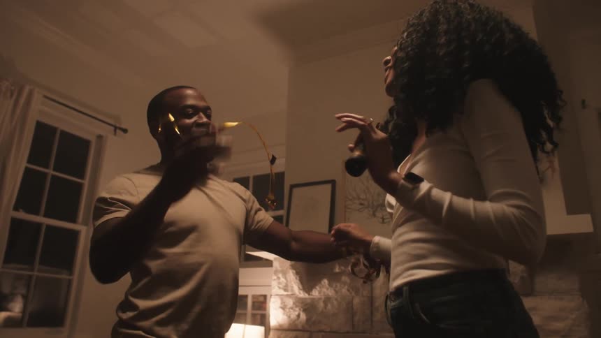 Black couple dancing in celebration at night in living room