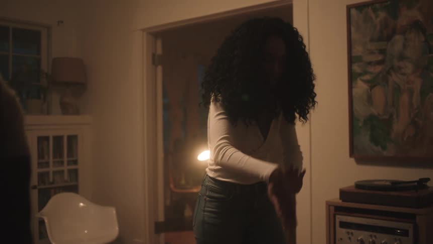 Black man and woman dance together in the living room at night