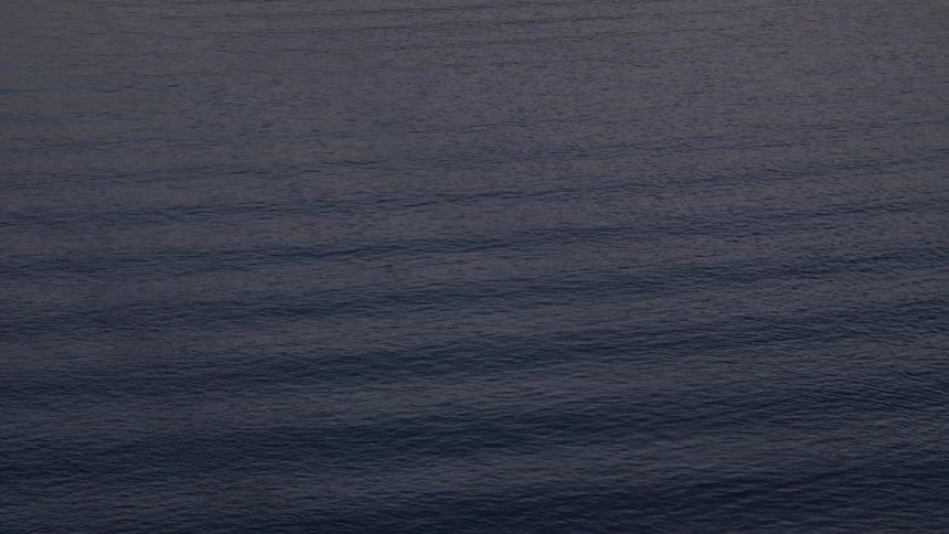 Small waves over the calm surface of the sea at sunset