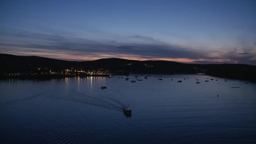 Boats move across a large body of water near a small coastal town