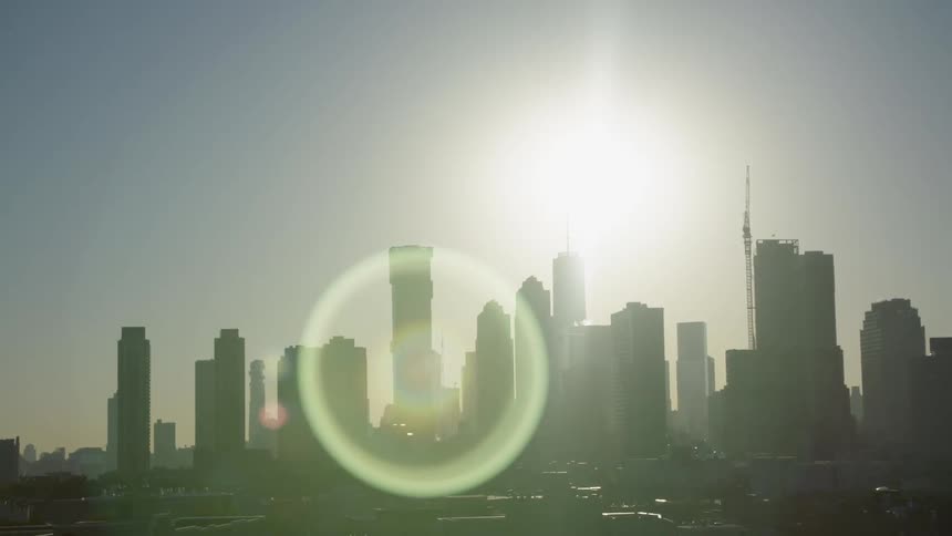 A city skyline with the sun in the background