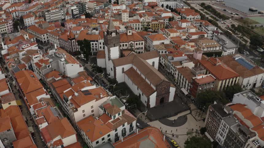 Red roofed buildings surround church separating it from water