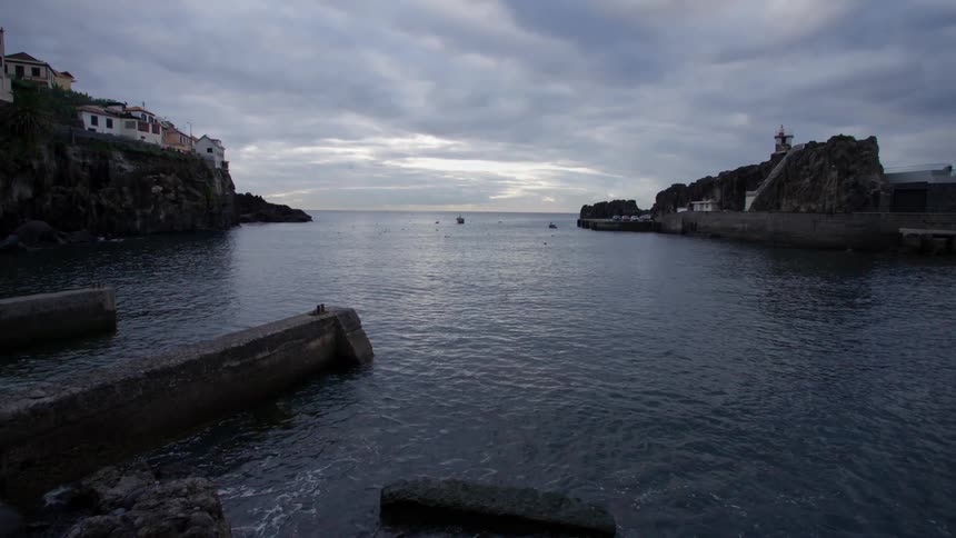 A small town sits above the ocean near a rocky cliff
