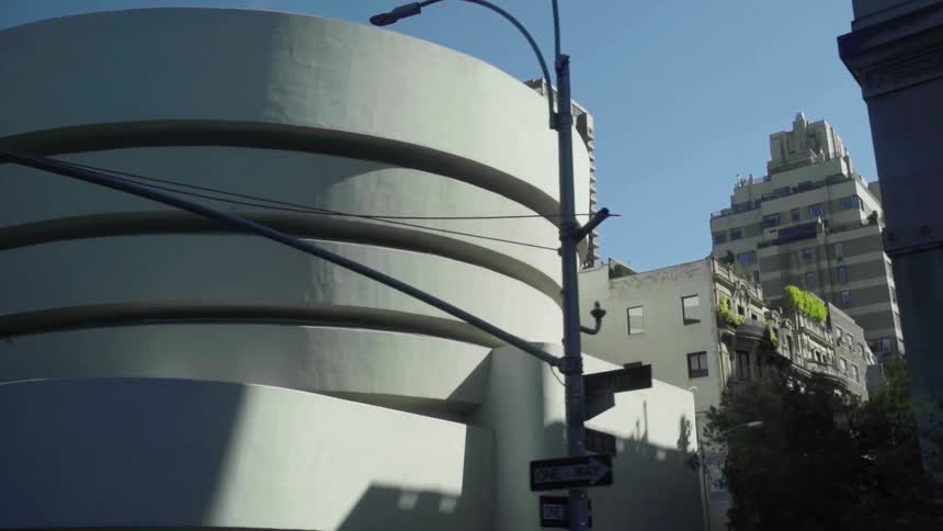 Guggenheim museum stands near intersection downtown on clear blue day