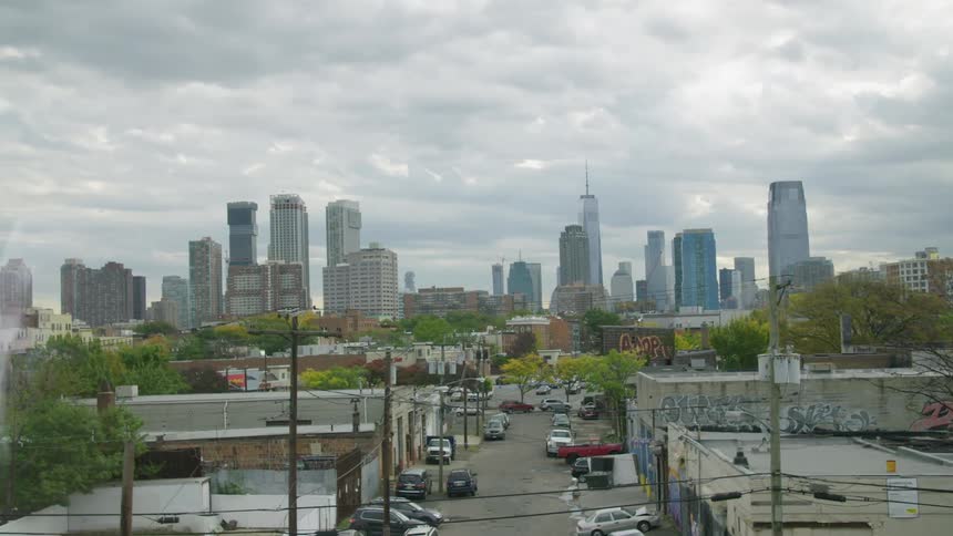 Green trees cover neighborhood bordering downtown skyscrapers under a cloudy sky
