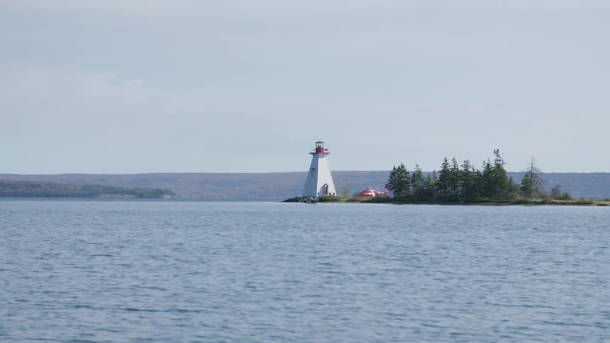 A lighthouse on a small island in the ocean on a sunny day