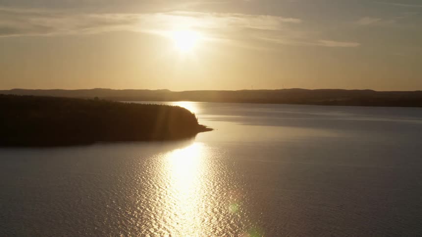 Aerial view of golden sunlight reflection on a river at sunset