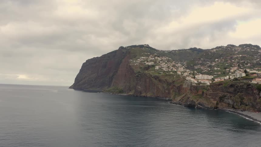 A small town sits on a mountain right off of the ocean
