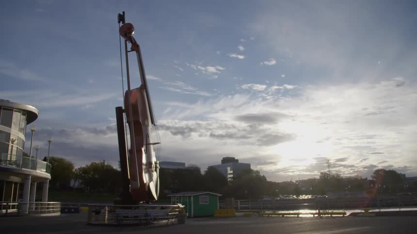 A large statue of a guitar in front of a building and off the water