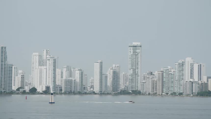 A boat driving through a lake in front of a city skyline