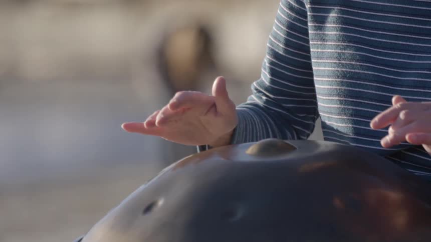 Woman outdoors tapping her hands on a metal object