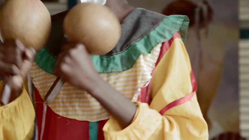 Woman in traditional dress plays maracas