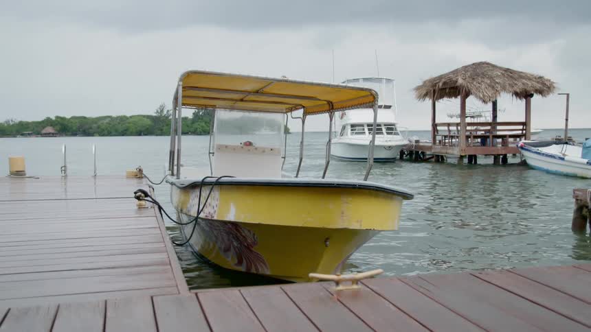 Yellow boat tied to dock swaying in the water on a tropical island