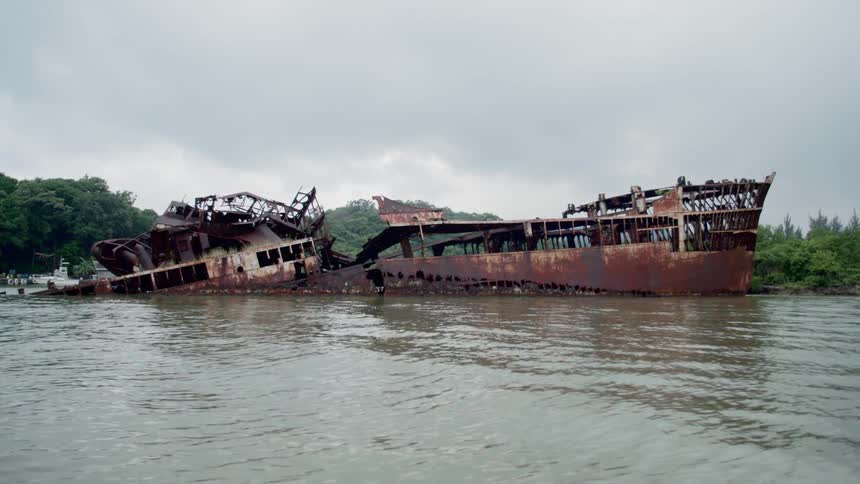 Abandoned rusty old wreckage sitting in murky waters in the jungle
